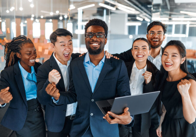 Business team working in office A team of successful businessmen of different nationalities in suits celebrating victory, success while standing in a modern office.